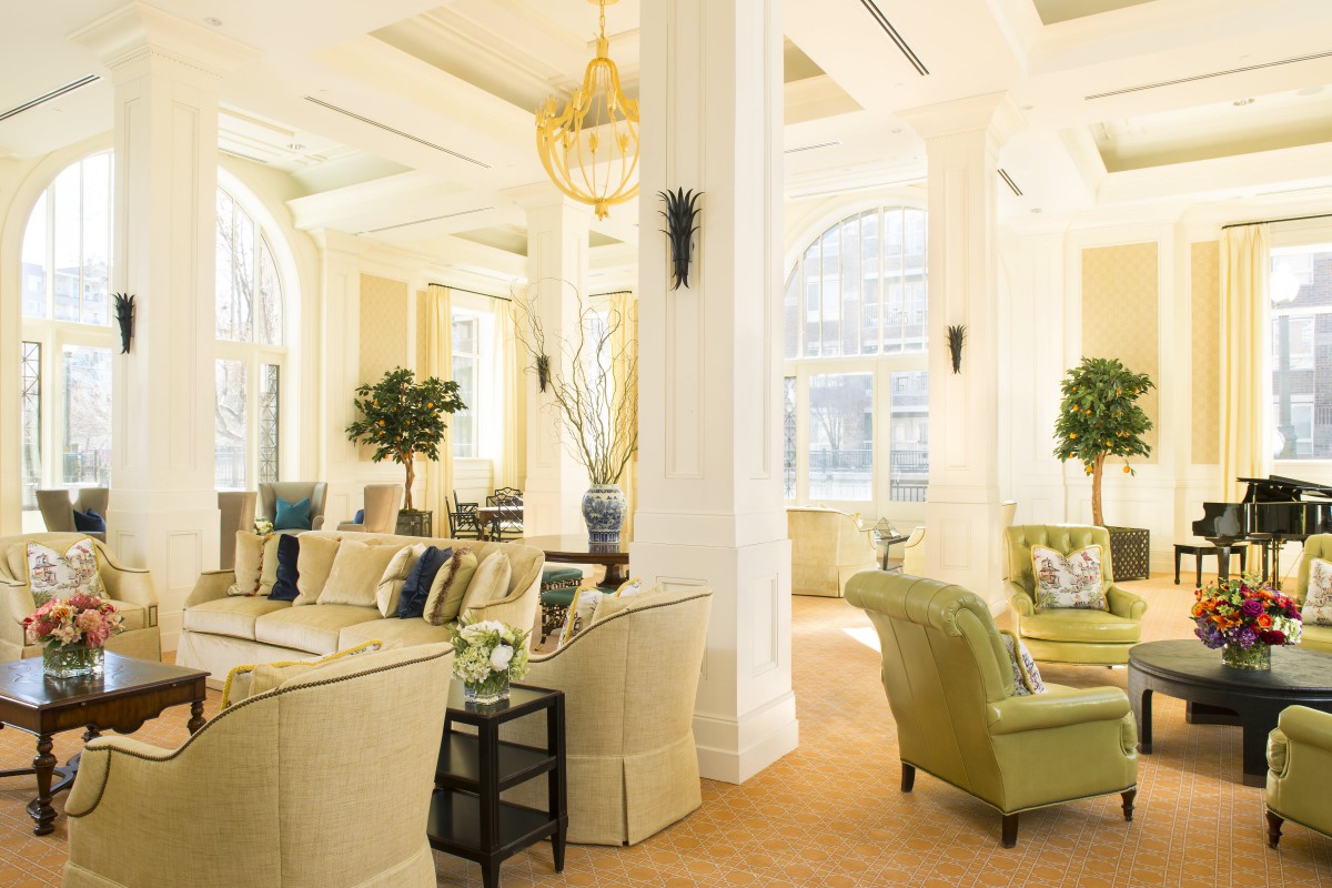 A luxurious living room with elegant furnishings, large windows, and indoor plants.