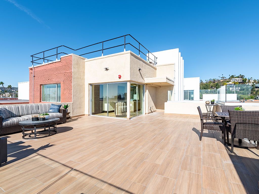 A spacious rooftop terrace with outdoor seating under a clear blue sky.