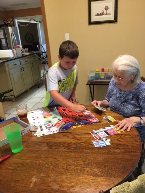 A grandmother and grandson enjoying a puzzle game together at the table.