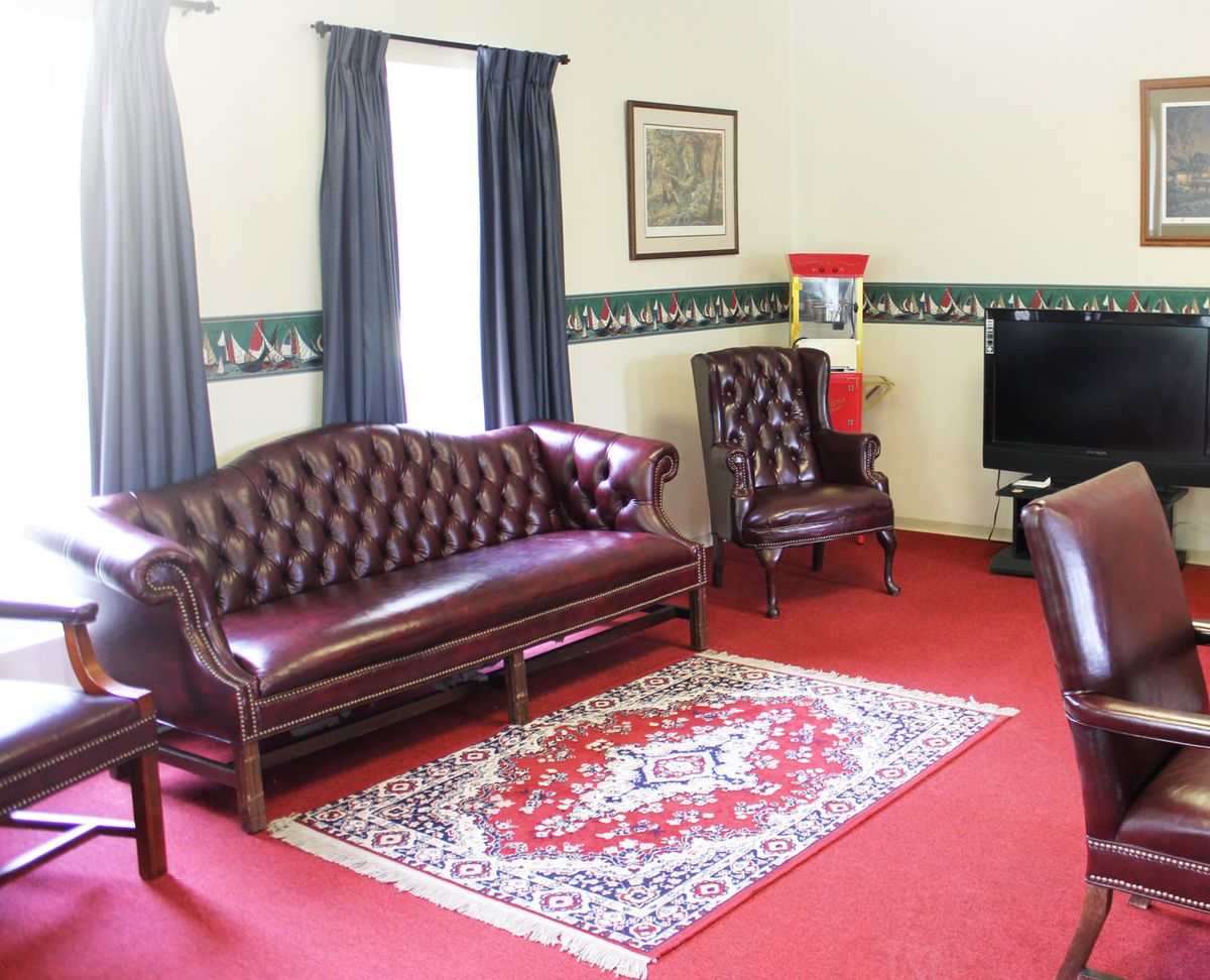 A traditional living room with a leather sofa, matching chairs, and a decorative rug.