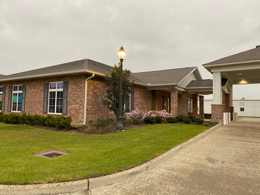 A stylish single-story brick house with a beautifully landscaped yard and outdoor lighting.
