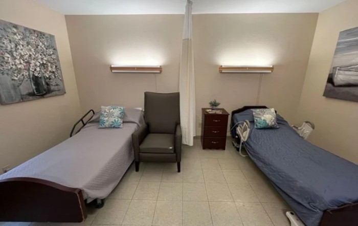 A hospital room with two patient beds separated by a curtain.