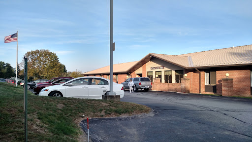 A view of a building with vehicles parked in front during a clear day.