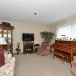 A cozy living room with a television, piano, and comfortable seating.