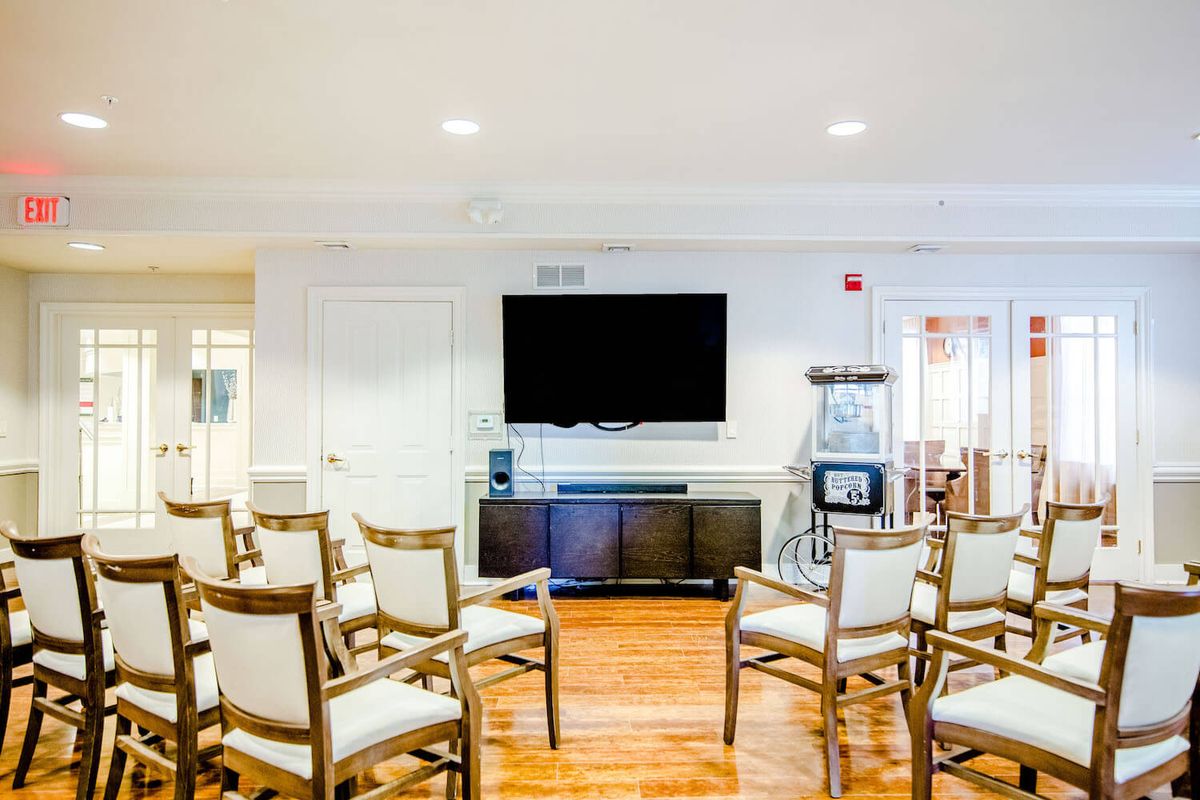 A well-lit meeting room arranged with chairs facing a large television.