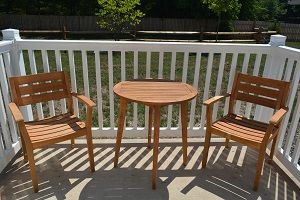 Wooden patio furniture set comprising a small table and two chairs on a deck.