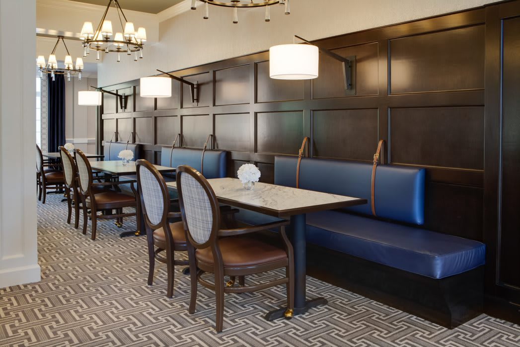 A cozy restaurant dining area featuring booth seating, elegant chandeliers, and carpeted flooring.