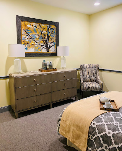 A cozy and elegantly decorated bedroom featuring a stylish dresser, modern lamps, and vibrant artwork.