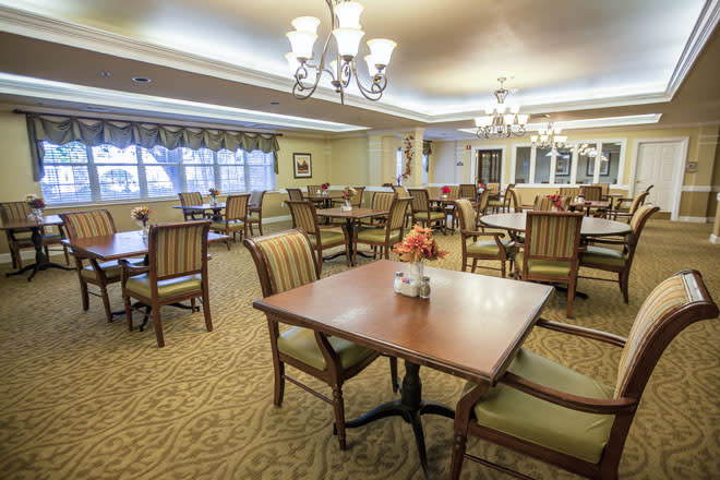 An elegant dining room with neatly arranged tables and chairs, featuring warm lighting and a cozy atmosphere.