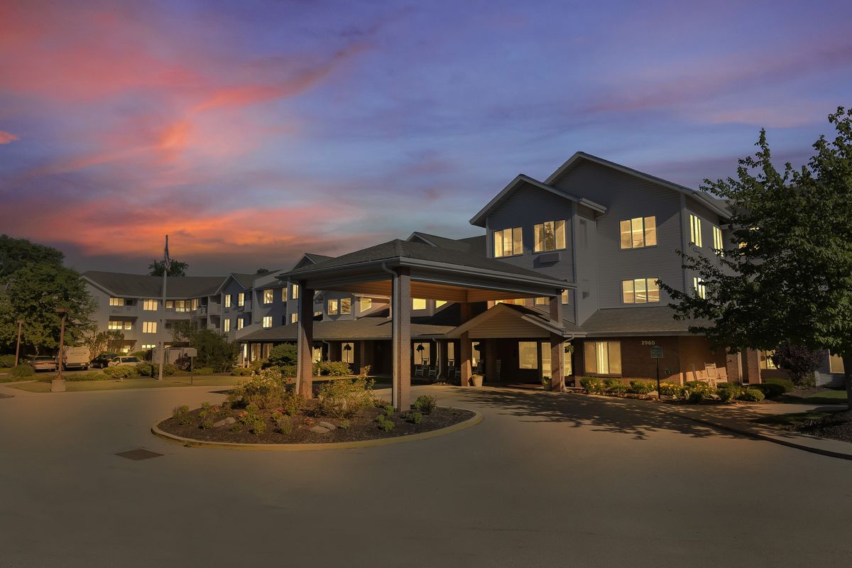 A spacious building exterior illuminated at twilight with a colorful sunset in the background.
