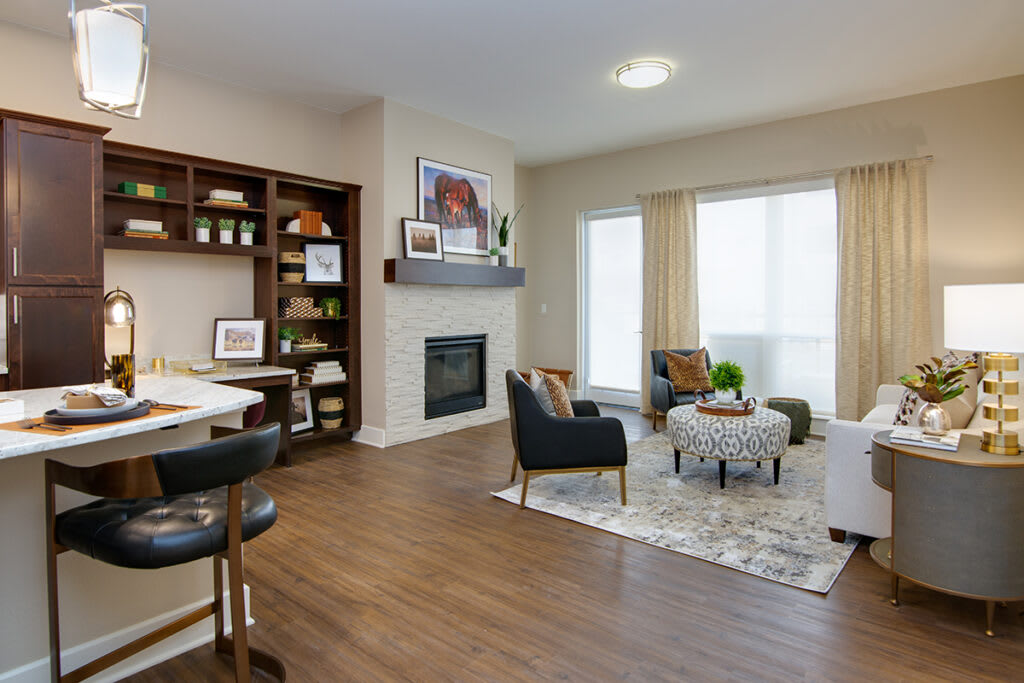 A modern living room with a fireplace, wooden floors, and ample natural light.