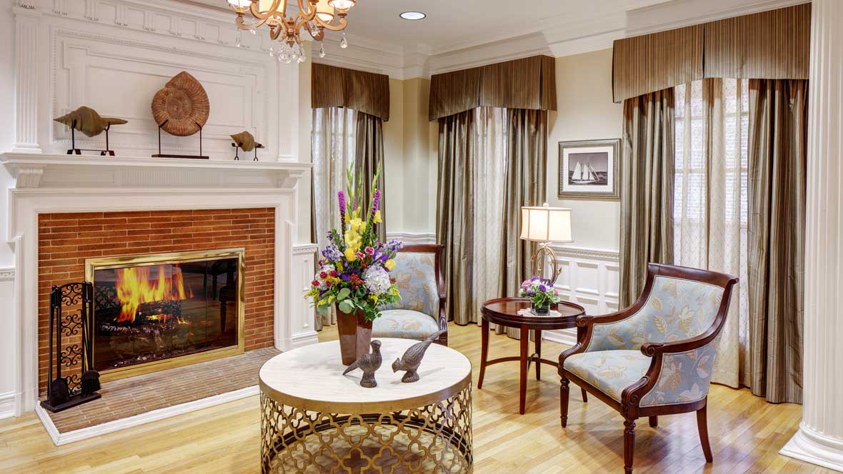 An elegantly decorated living room featuring a fireplace, cozy seating, and floral arrangements.