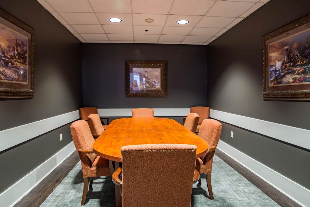 A small conference room featuring a wooden meeting table surrounded by six upholstered chairs.