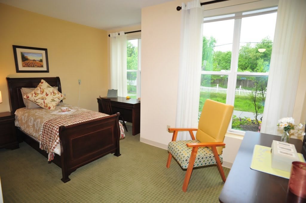 A cozy bedroom with a single bed, desk, and a chair by the window.