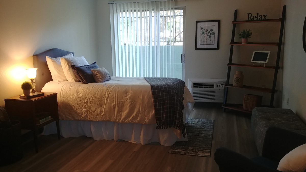 A cozy bedroom with a neatly made bed, natural lighting from a nearby window, and stylish home decor.