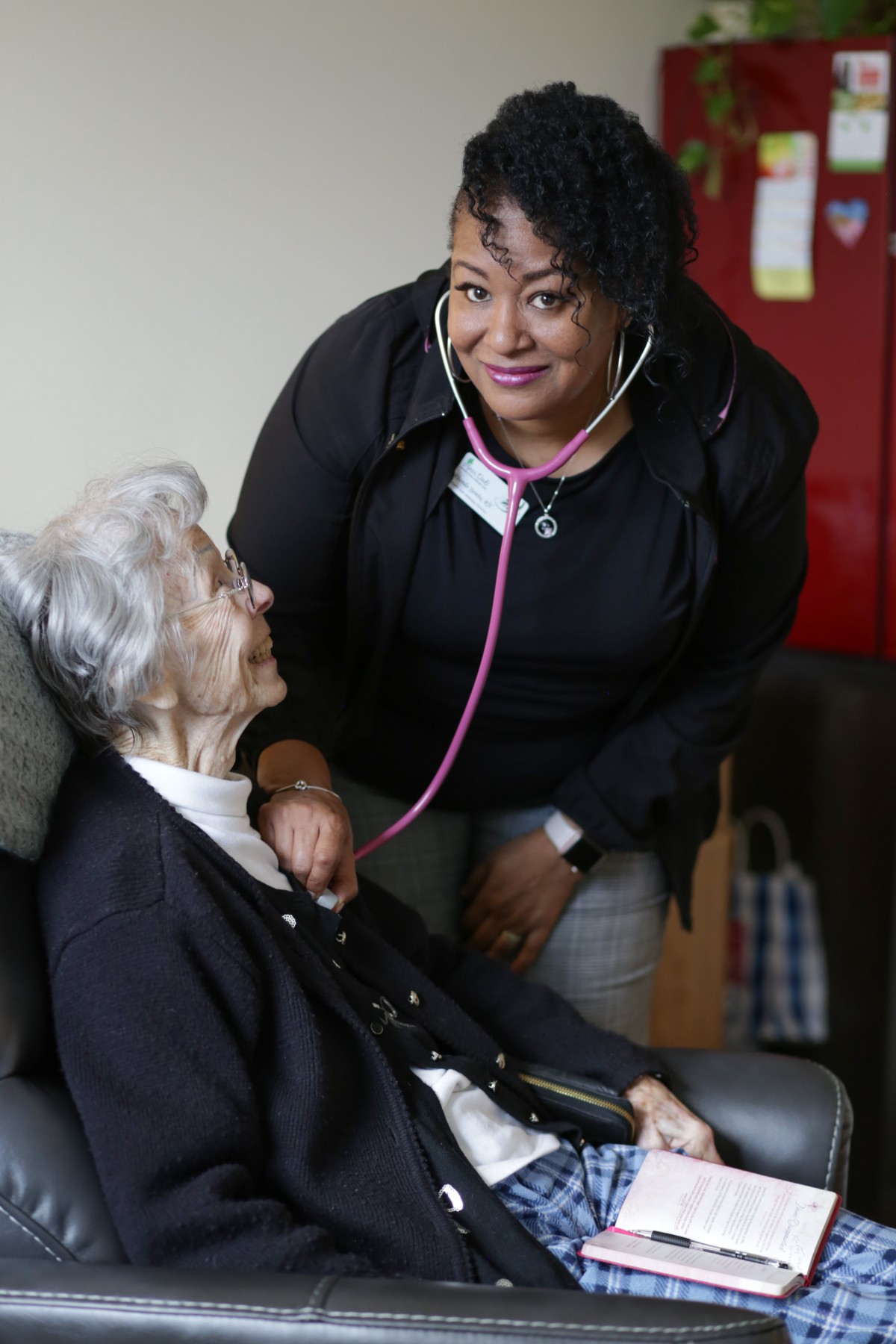 A nurse uses a stethoscope to check on an elderly patient, showcasing compassionate healthcare.