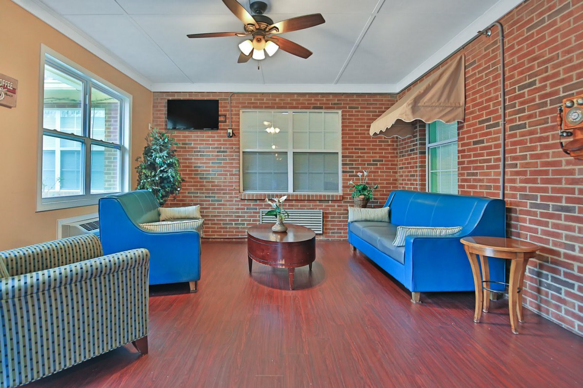 A cozy living room with blue sofas, a wooden coffee table, and brick walls.