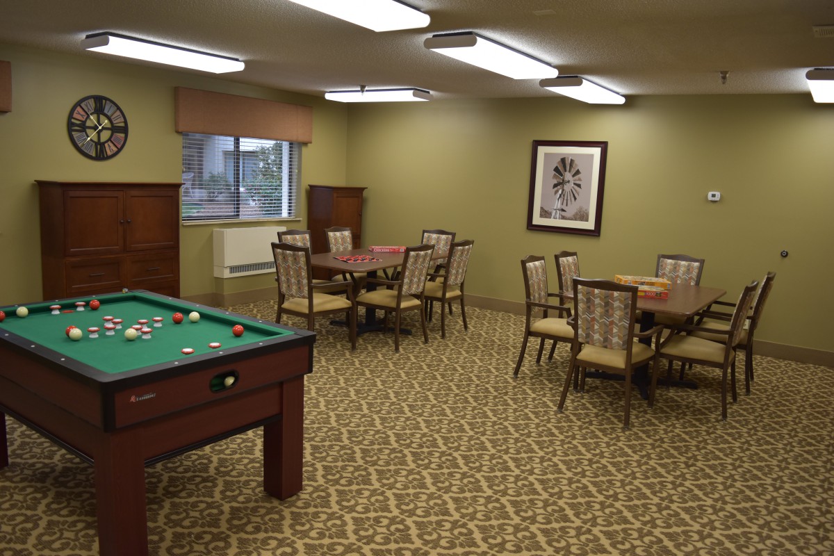 A cozy game room featuring a pool table and multiple seating areas.