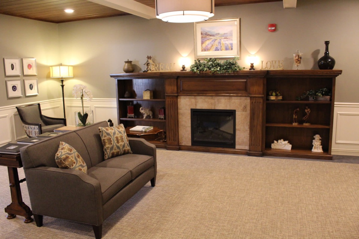 A cozy living room featuring a fireplace, sofa, and decorative shelves.