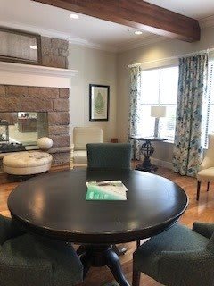 A cozy living room with a round table and chairs near a fireplace.