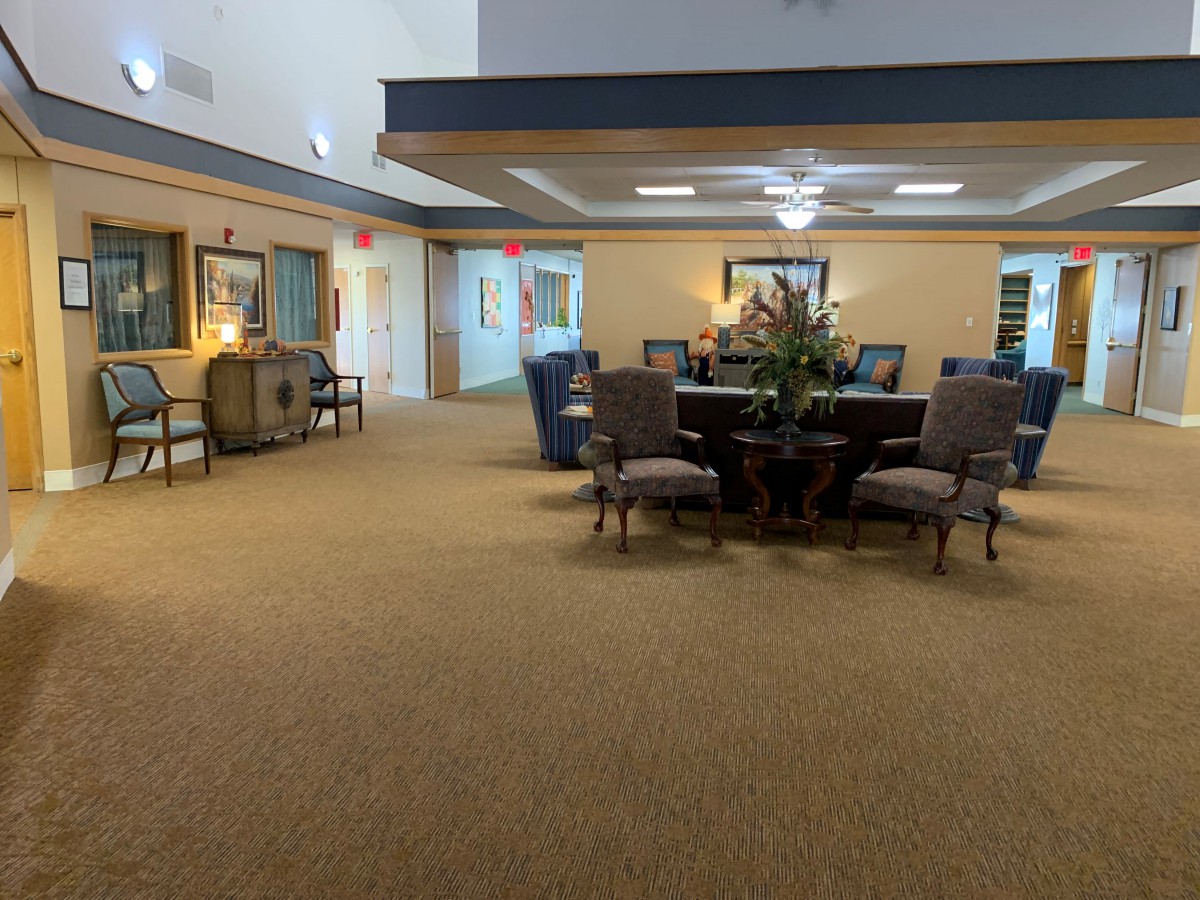 A spacious lobby area with a central table surrounded by chairs, featuring elegant decor and warm lighting.