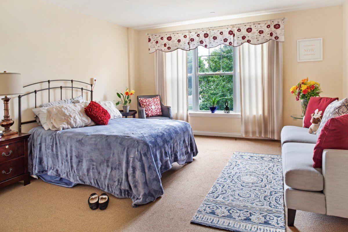 A cozy bedroom with a bed, window, and carpeted floor.