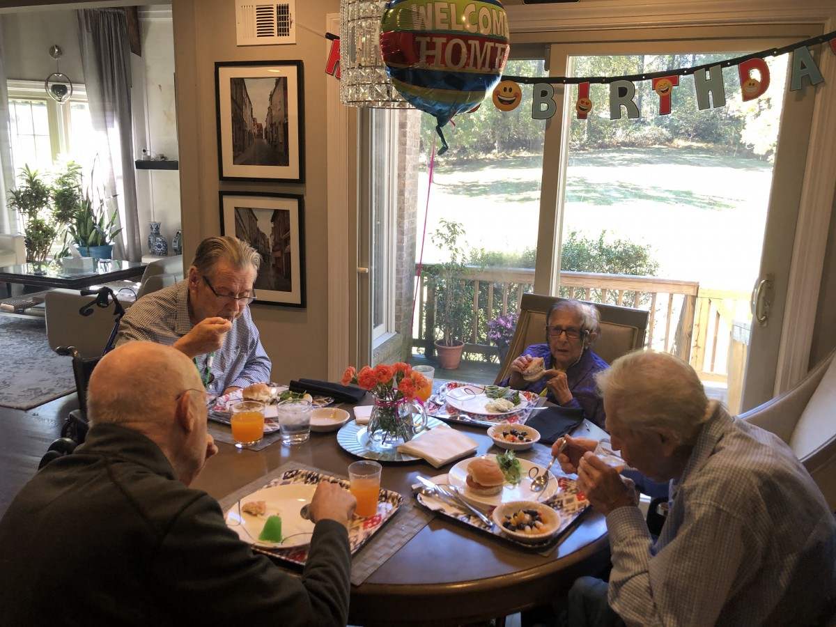 A group of seniors enjoying a meal together at a decorated dining table.