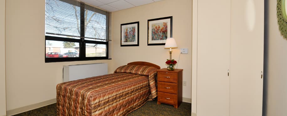 A cozy bedroom with a single bed and wooden furniture, featuring two pieces of artwork on the wall.