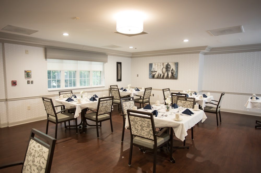 A neatly arranged dining room with elegantly set tables and chairs.