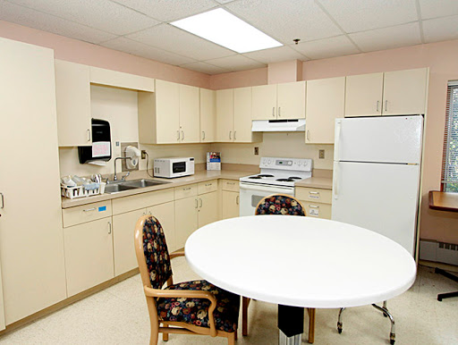 A modern kitchen setup with light-colored cabinets and a round table.