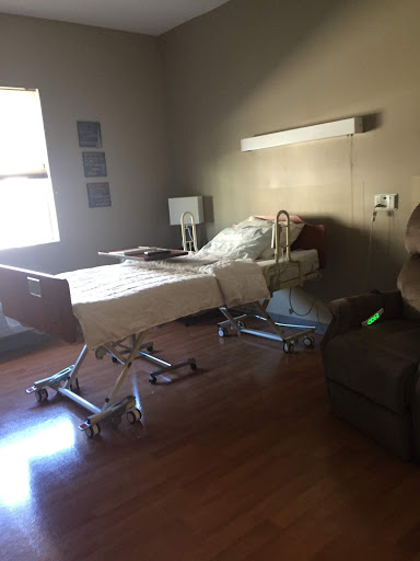 A well-equipped hospital room featuring a bed, a comfortable chair, and natural light.