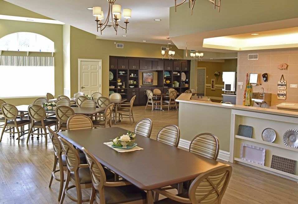 A cozy dining room with multiple tables and chairs, featuring warm lighting and elegant decor.