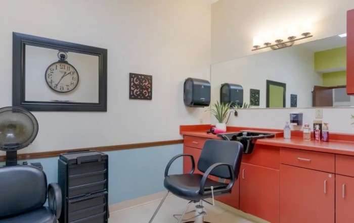 A tidy hair salon setup featuring a styling chair, mirror, and wall clock.