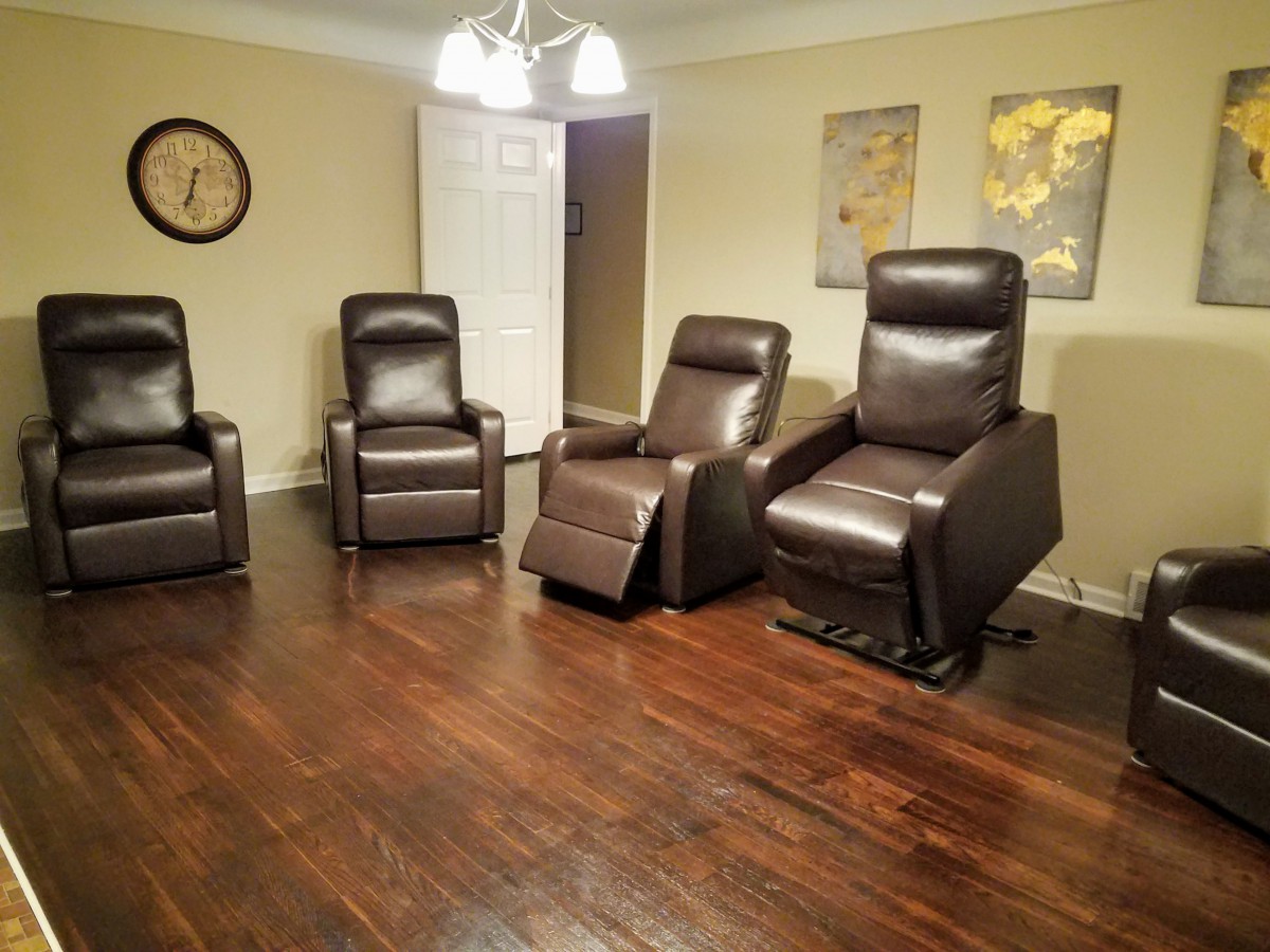 A cozy living room with four recliner chairs arranged on a hardwood floor.