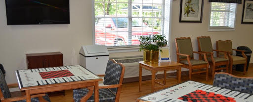 A cozy interior space featuring wooden furniture, a potted plant, and natural light streaming through the window.