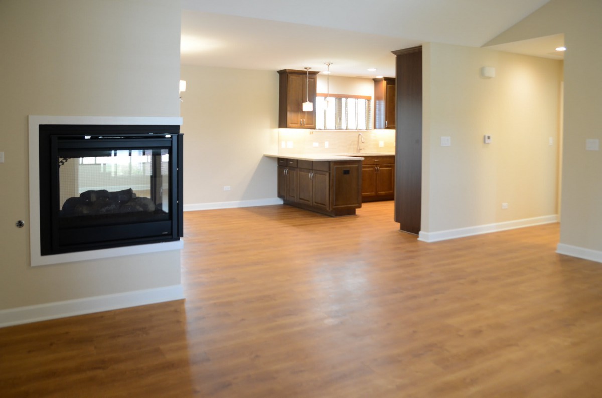 Open concept living room and kitchen with hardwood flooring and a fireplace.