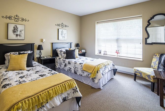 A cozy bedroom featuring twin beds with decorative bedding, a large window, and stylish interior decor.
