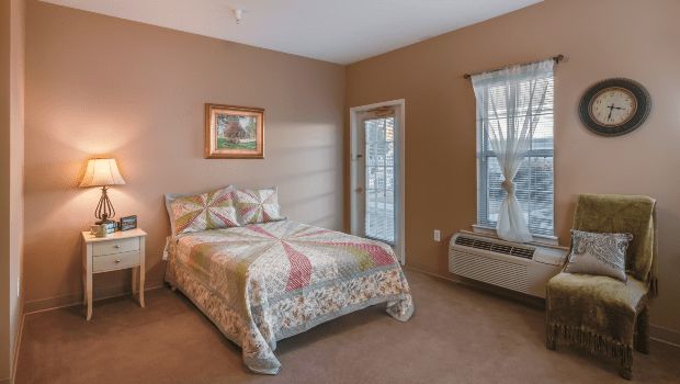 A cozy bedroom with a bed, window, and air conditioning unit.