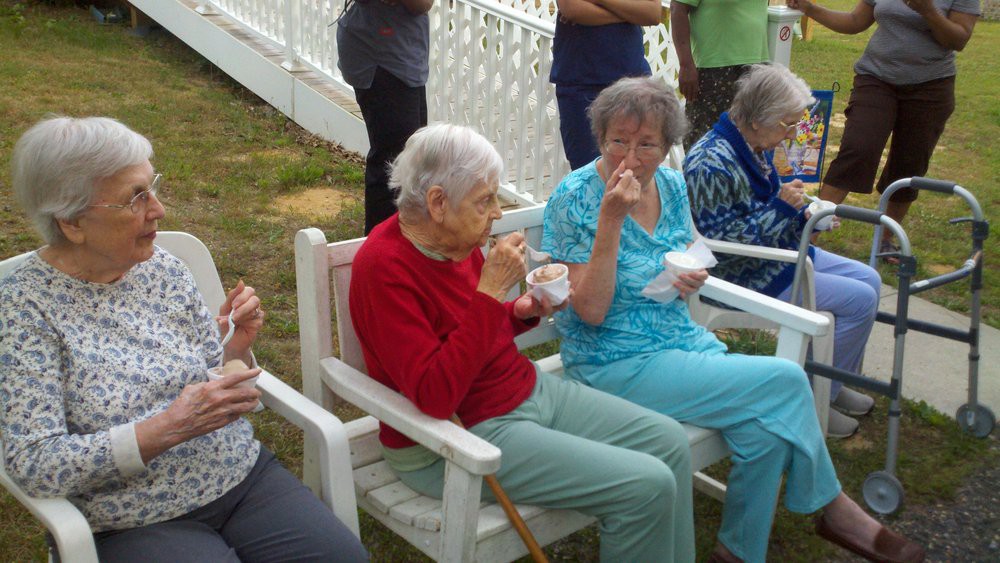 A group of elderly people sitting outside and enjoying a meal together.