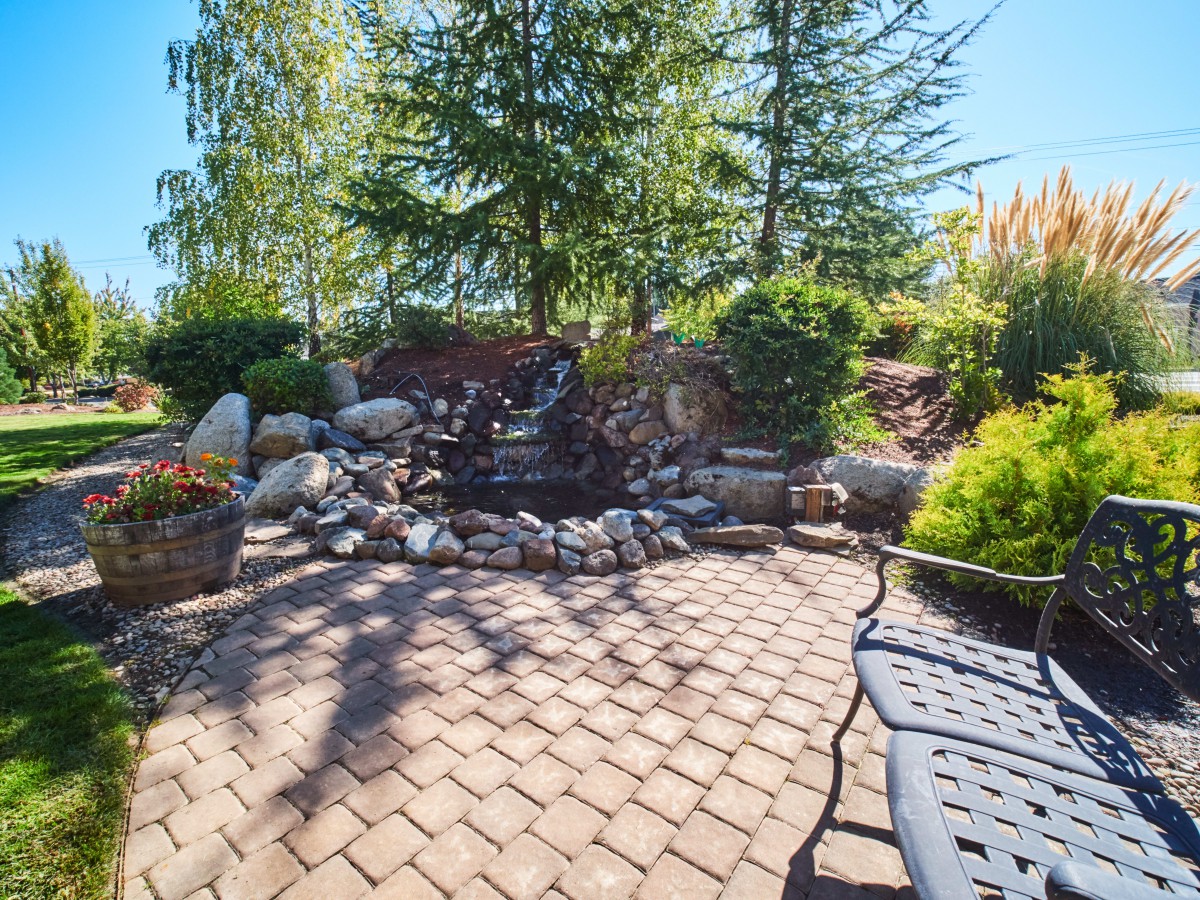 A tranquil garden patio with lush greenery and a stone pathway.