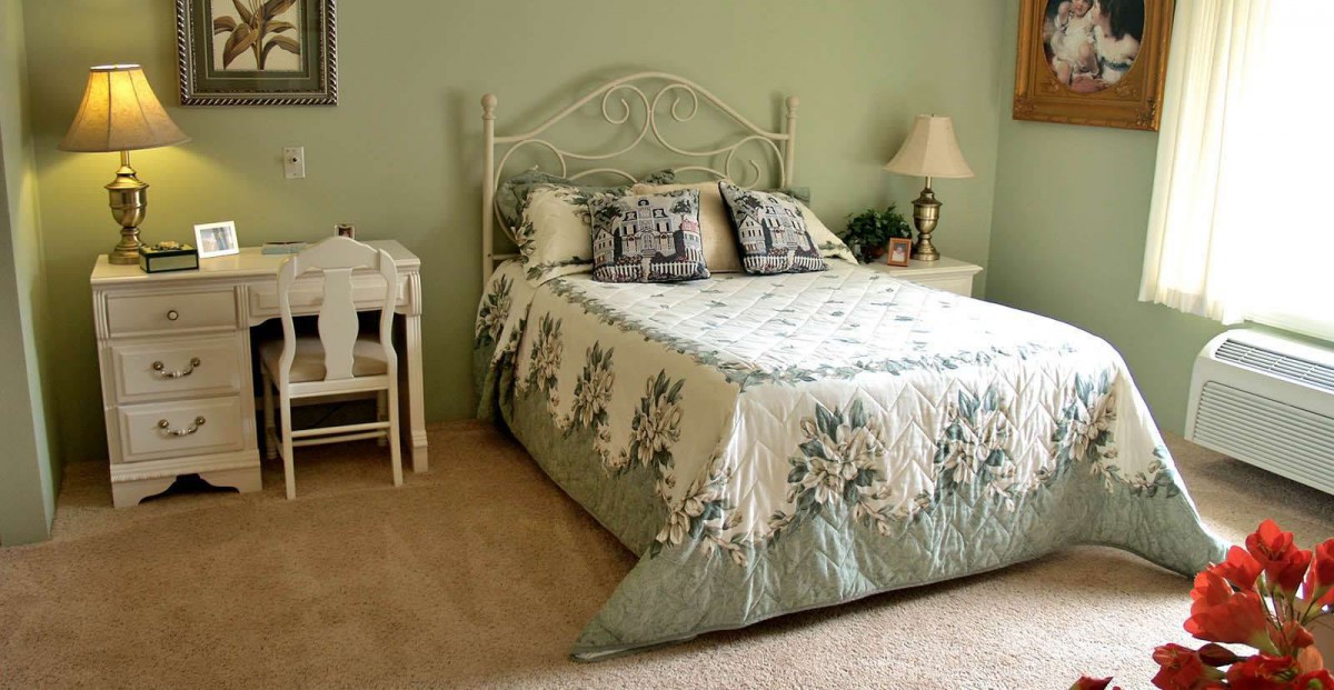 A cozy bedroom with a vintage-style quilt and decorative pillows.