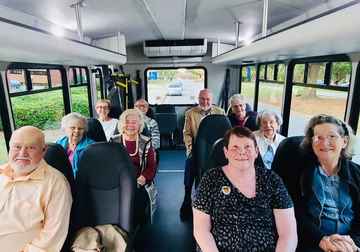 A group of elderly passengers seated inside a bus.