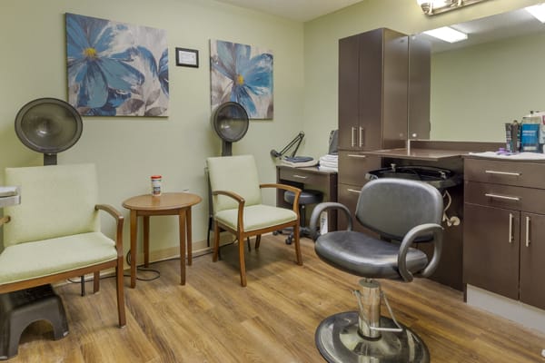 A cozy salon interior with chairs, a hairdryer, and wall artwork.