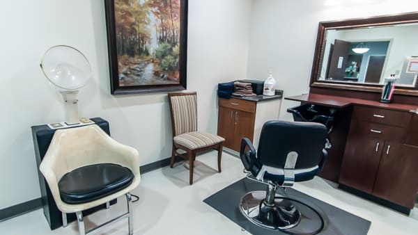 A small salon interior with chairs, a mirror, and a painting on the wall.