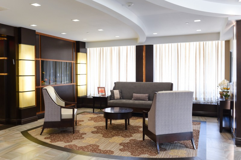 A modern lobby area featuring a sofa, chairs, and a coffee table on a patterned carpet.