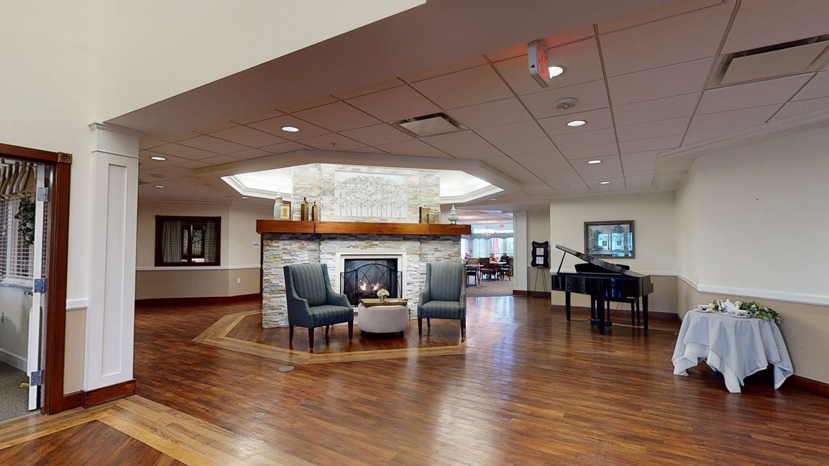 A modern lobby with a cozy seating area, featuring a fireplace and a piano.