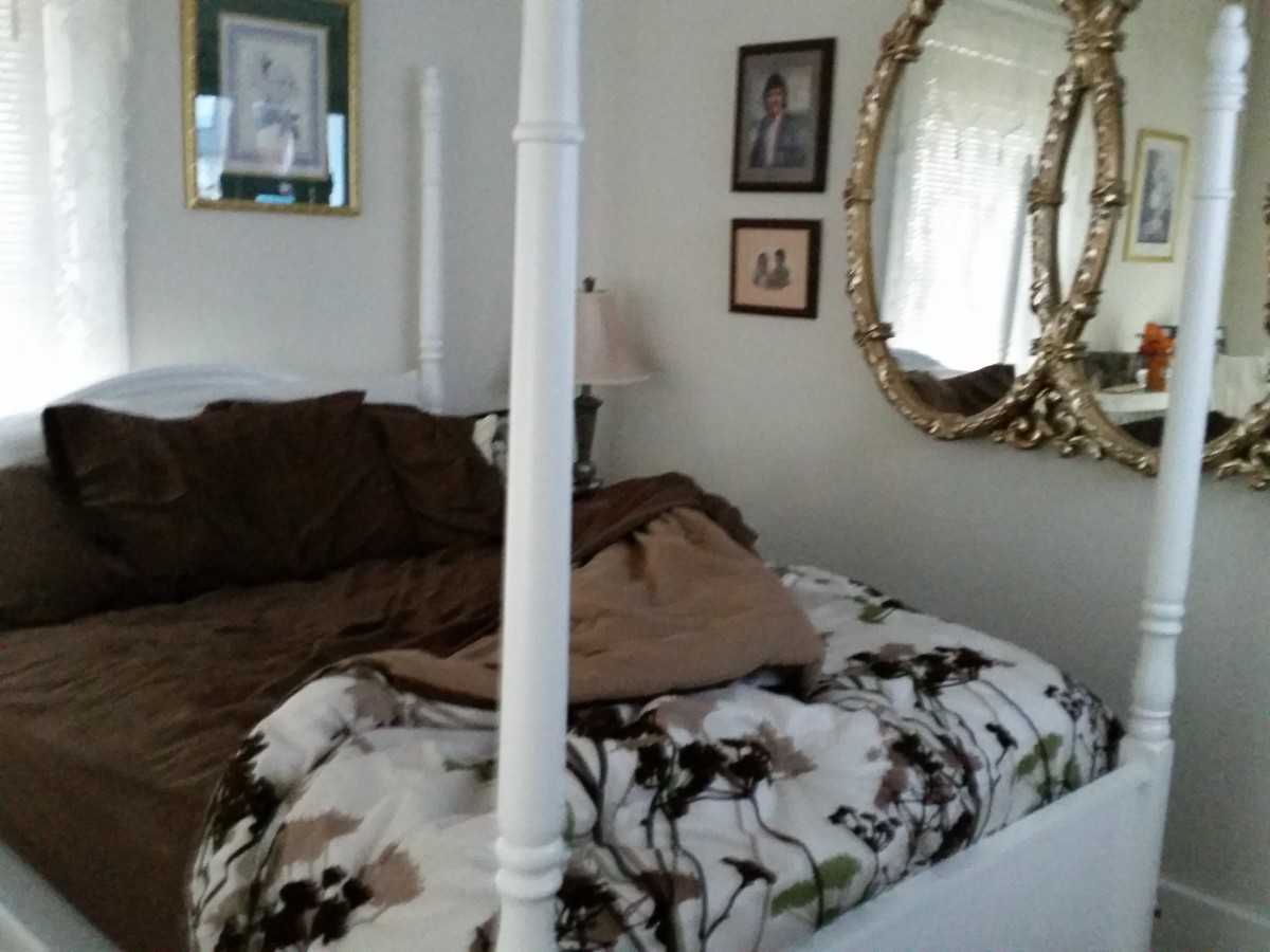 A cozy bedroom with a four-poster bed and an ornate mirror on the wall.