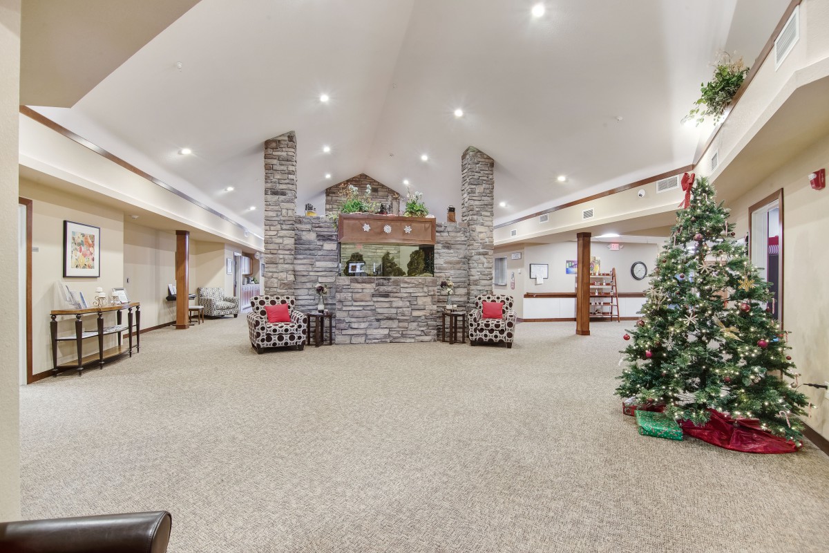 A cozy lobby with holiday decorations, featuring a stone fireplace and Christmas tree.