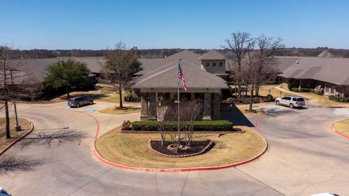 A suburban building with a flagpole in the roundabout on a sunny day.