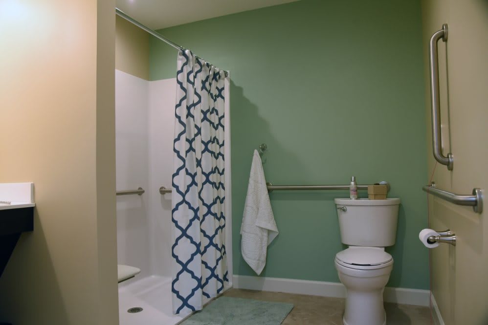 A neatly organized bathroom with a green wall and a shower area.